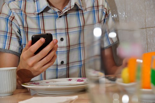 Checking email on mobile phone at breakfast free photo