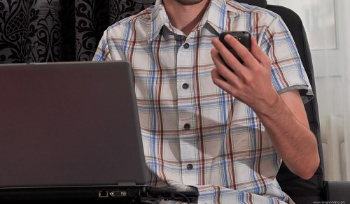Man in shirt checking mobile phone in office free photo